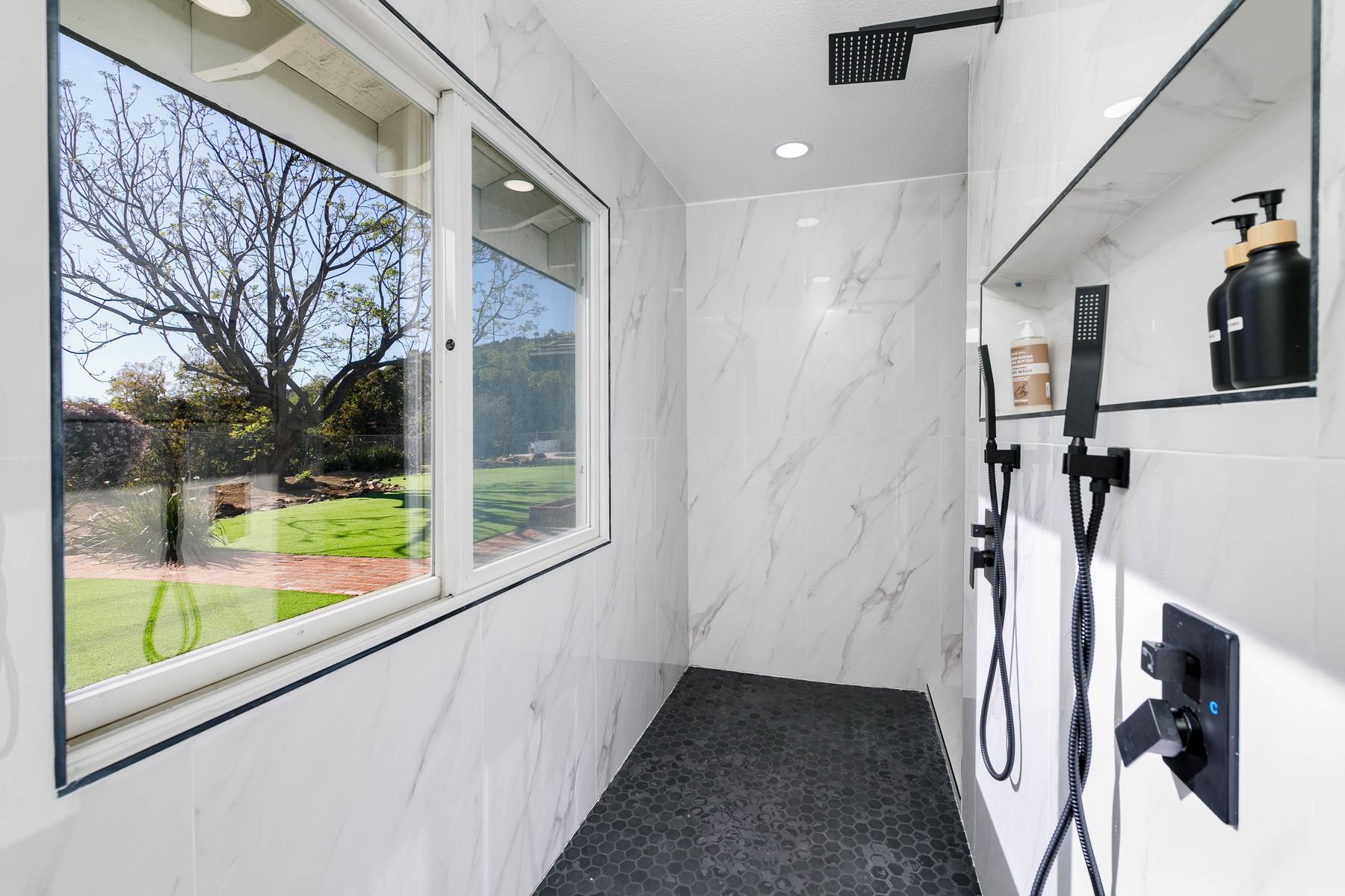 Marble walk-in rain shower with window overlooking the yard